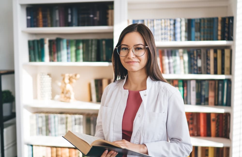 A smiling female medical student studies in a reference library