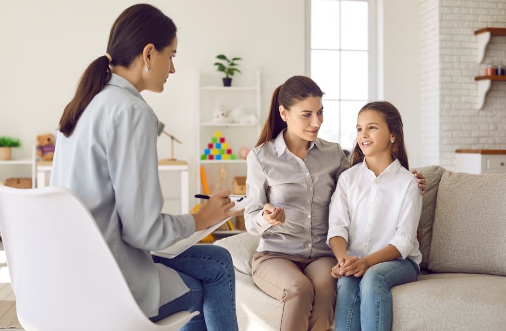 A mother and her pre-teen daughter talk with a family counselor