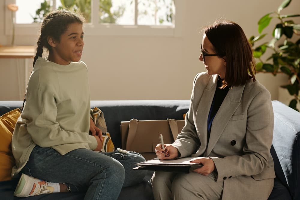 A social worker meets with an African American female teenager during a home visit.