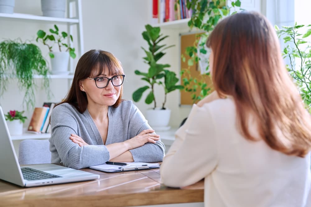 A college mental health counselor meets with a young female college student.