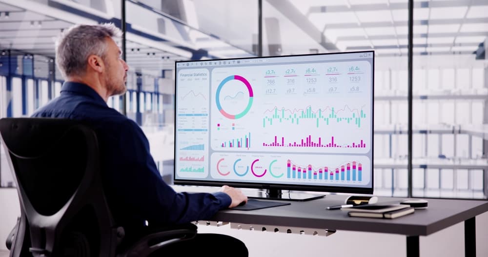 A business analyst reviews a data dashboard on his computer.