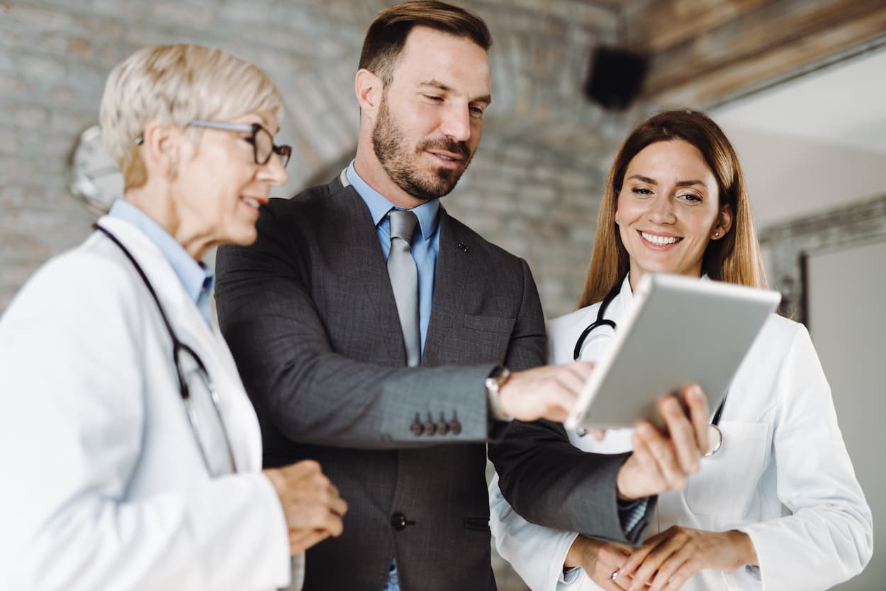 A healthcare administrator consults with two female doctors.