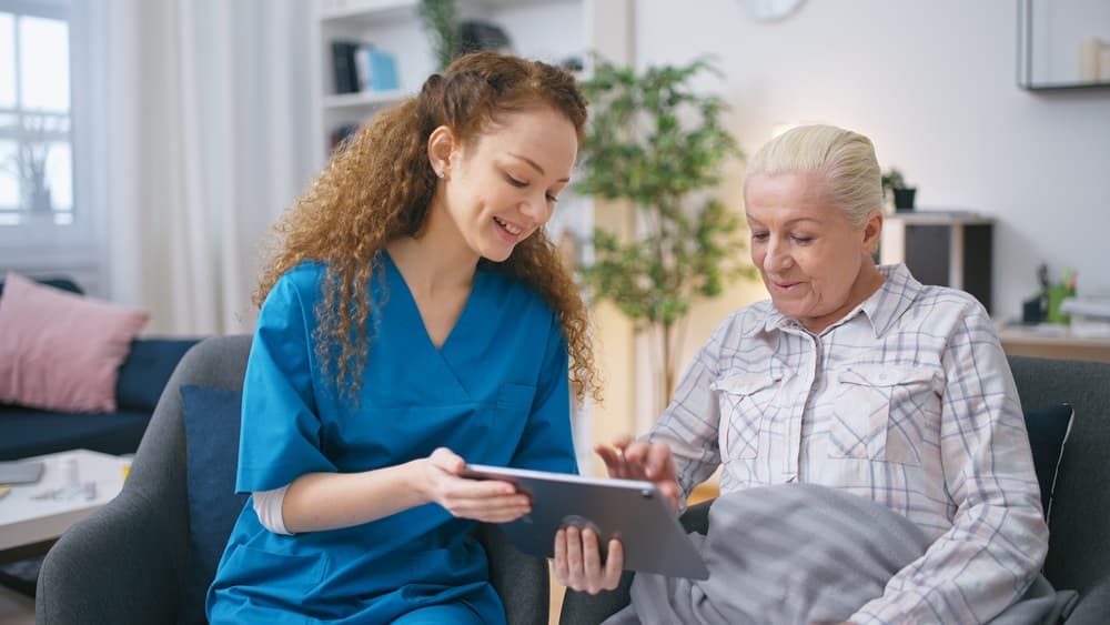 A smiling social worker explains care with her elderly client