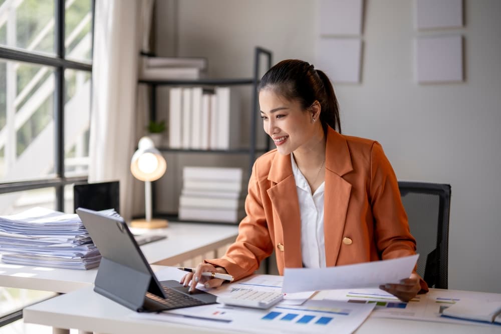 A smiling accountant works at her desk reviewing financial statements