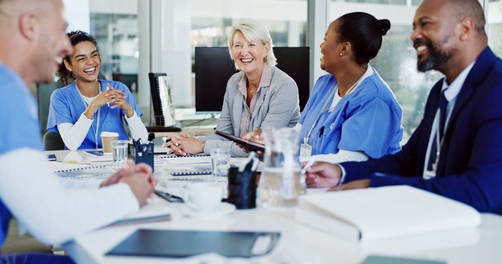 A smiling healthcare administrator meets with her happy-looking staff.