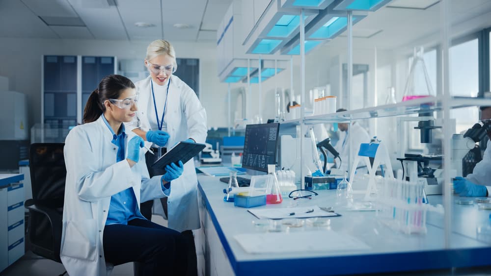 Two lab technicians work in their lab while reviewing test results