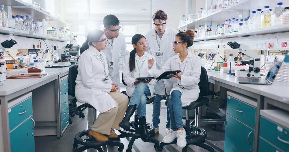 A diverse team of health science researchers grouped together in their lab to discuss research results.