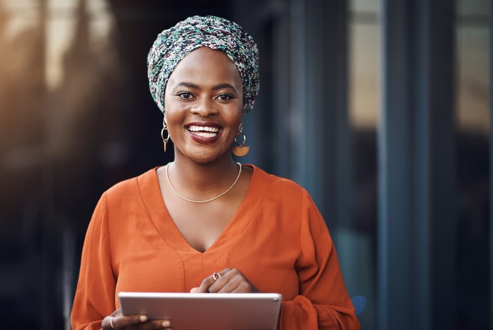 A smiling African-American mental health researcher holds a tablet while collecting research data
