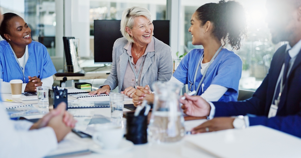 A healthcare manager conducting a staff meeting with administrators and nurses.