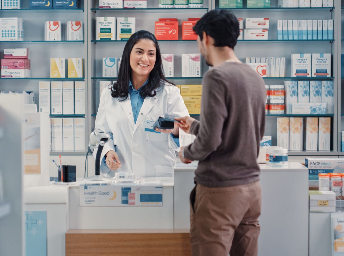 Pharmacy Drugstore: Man Chooses Medicine, Comes to the Counter, Talks to Beautiful Pharmacist Cashier, Pays for the Health Care Products at the Checkout Counter Using Contactless Payment Credit Card